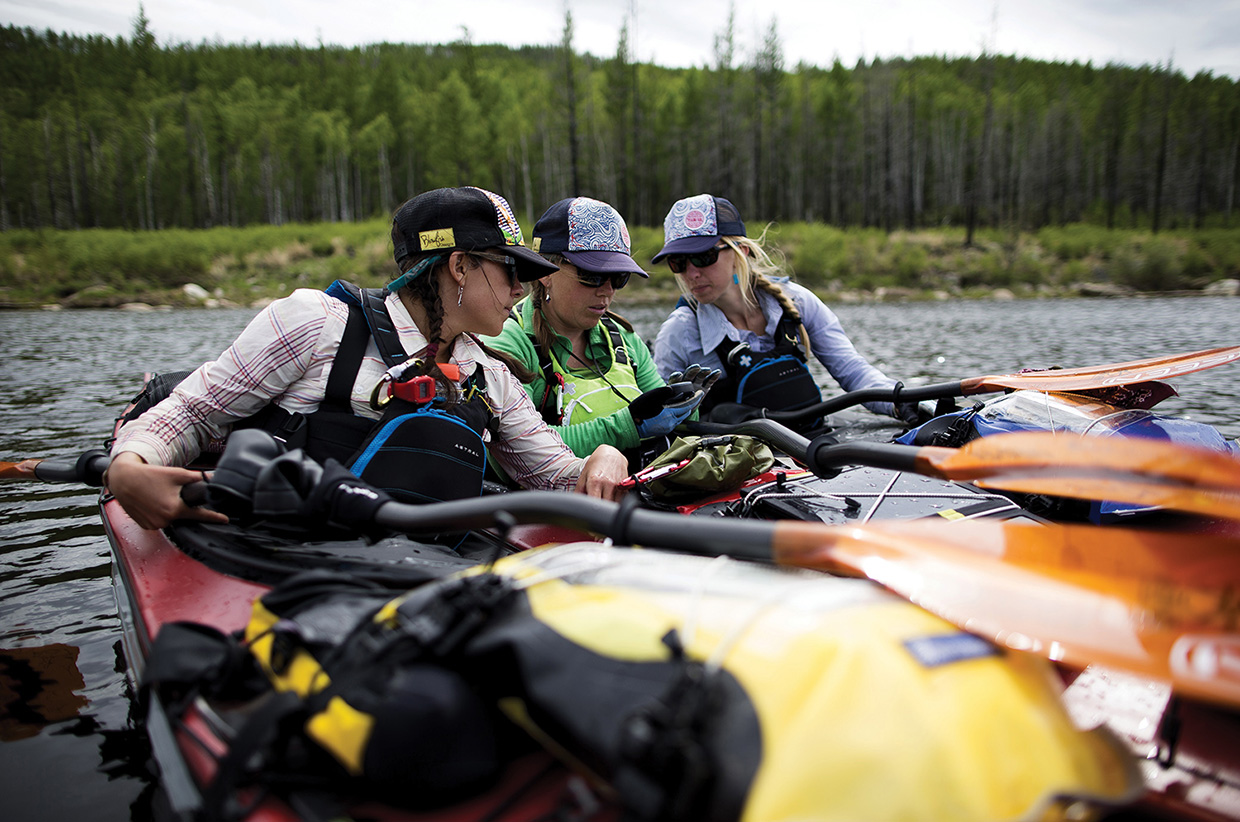 The team (L to R) Amber, Sabra and Becca check the GPS to figure out the mileage they need to paddle before stopping for the day.